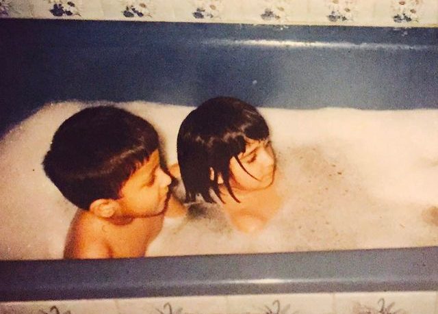 In this childhood frame, She taking a bath with her brother.