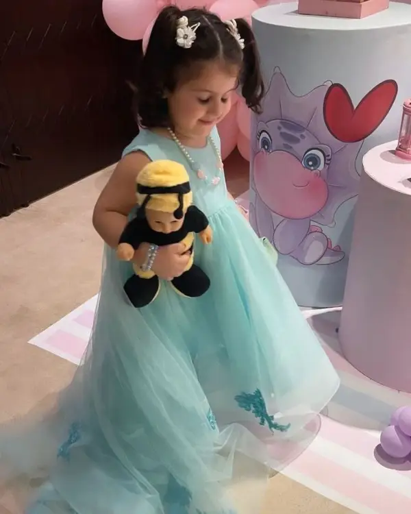 Amal Muneeb plays with her doll after cutting the birthday cake