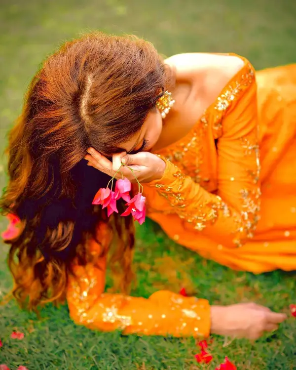 The actress wears an orange dress as she sits in a garden