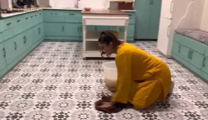 The host is cleaning the floor of her kitchen