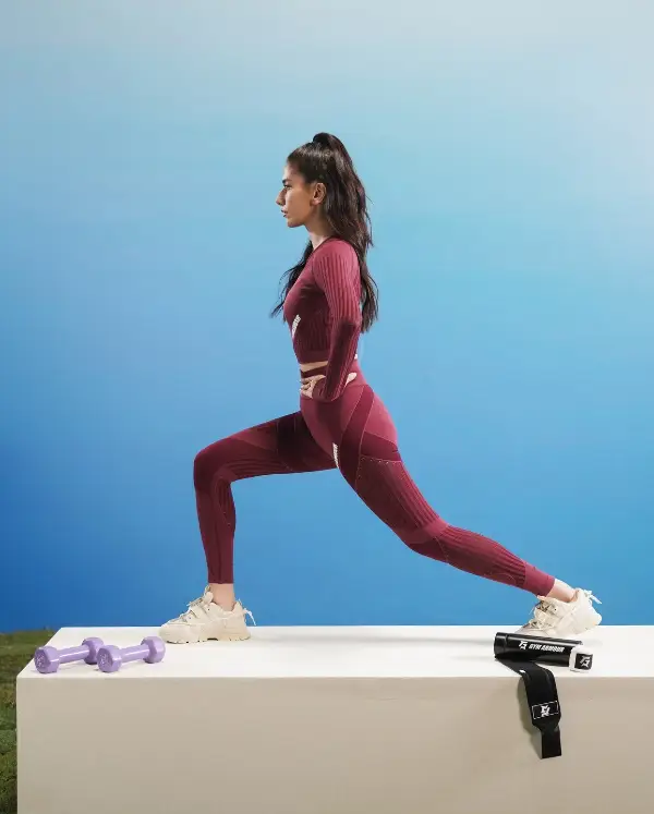 The actress exercises while wearing a maroon legging and white sneakers