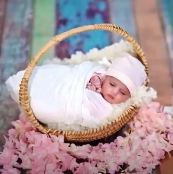 A beautiful picture of Baby Aizal resting in her crib as she wears a white dress