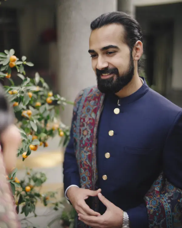 The groom wears a blue sherwani in this photo